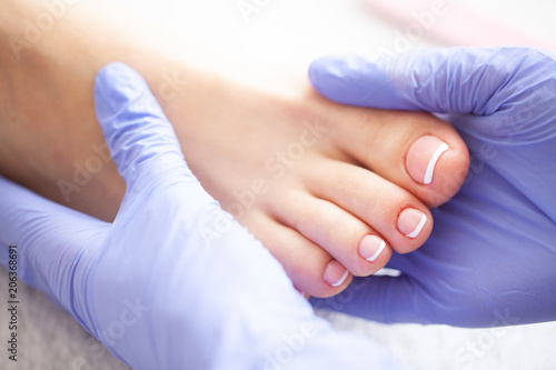 Hand and Nail Care. Beautiful Women's Feet with Pedicure in Beauty Salon. Master Doing Massage Feet. Spa Manicure. photo