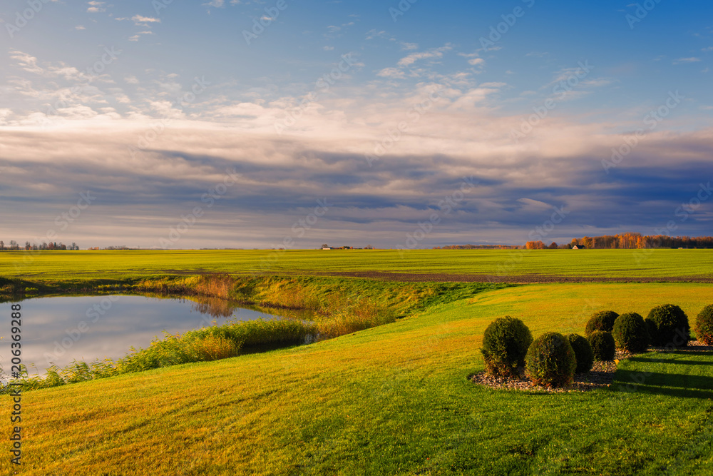 Obraz premium field with lake on sunset in Latvia on cloudy sky background