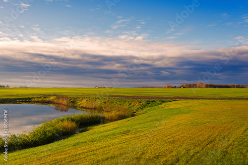 field with lake on sunset in Latvia on cloudy sky background