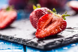 Fresh ripe strawberries washed with water on blue table