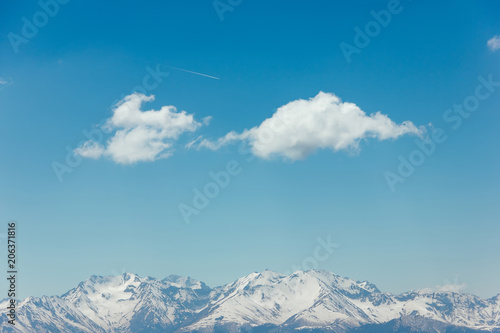 Mountains with peaks covered with snow, white clouds on blue sky, Caucasus