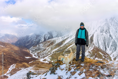 Man and dog labrador hike the cloudy mountains