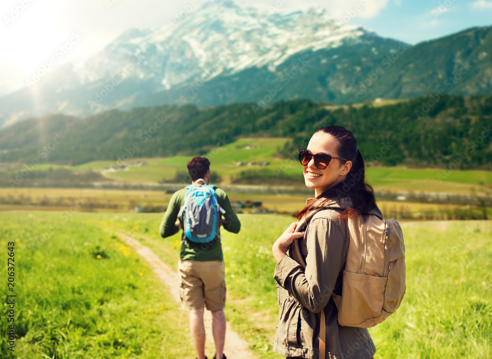 travel, tourism and people concept - happy couple with backpacks walking along country road over mountains background