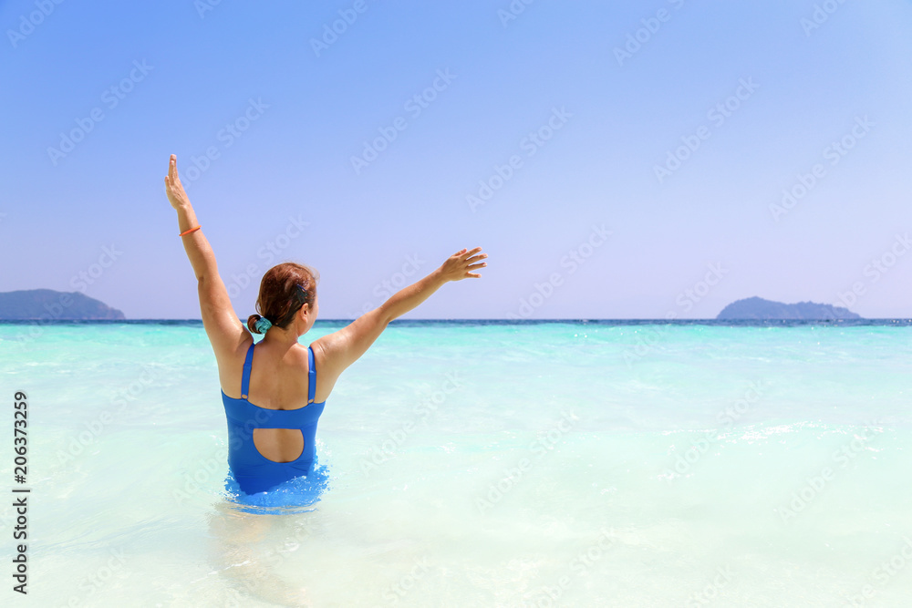 Woman in blue swiming suite raised hands up with happy in summer and beautiful sea Woman in blue swiming suite raised hands up with happy in summer and beautiful sea
