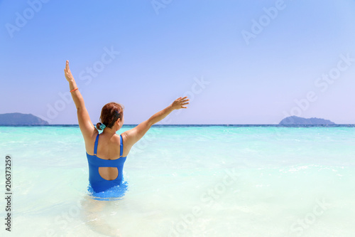Woman in blue swiming suite raised hands up with happy in summer and beautiful sea