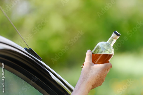 Alcohol, bottle,  car and concept of drunk driving - the person holds in hand a bottle with alcoholic drink, driving the car. Tonted photo