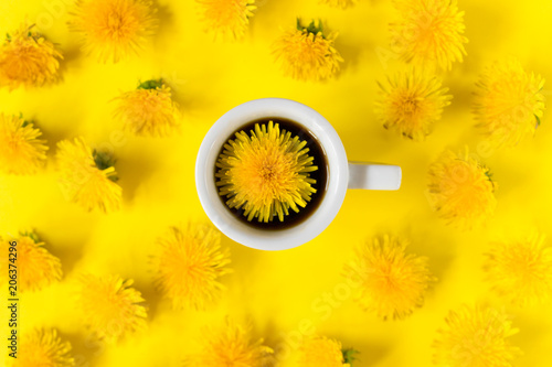 A cup of coffee with a dandelion on a yellow background with a floral pattern. Creative layout. Flat lay. Place for text