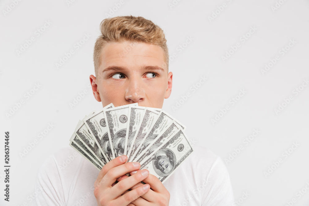 Portrait of a surprised teenage boy holding money banknotes Portrait of a surprised teenage boy holding money banknotes