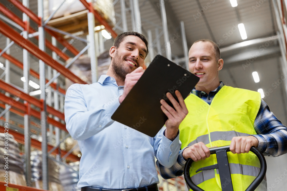 logistic business, shipment and people concept - businessman with clipboard and warehouse worker with loader logistic business, shipment and people concept - businessman with clipboard and warehouse worker with loader
