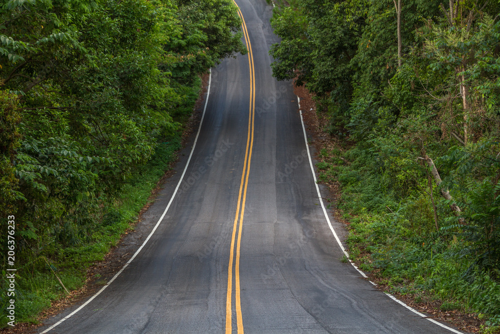 Beautiful mountain asphalt road with curve and double yellow line ,  road runs along the edge of the forest in chiang mai, Thailand