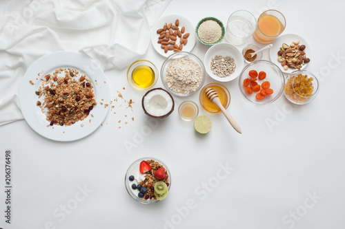 Ingredients for a healthy breakfast - granola, honey, nuts, berries, fruits, top view.