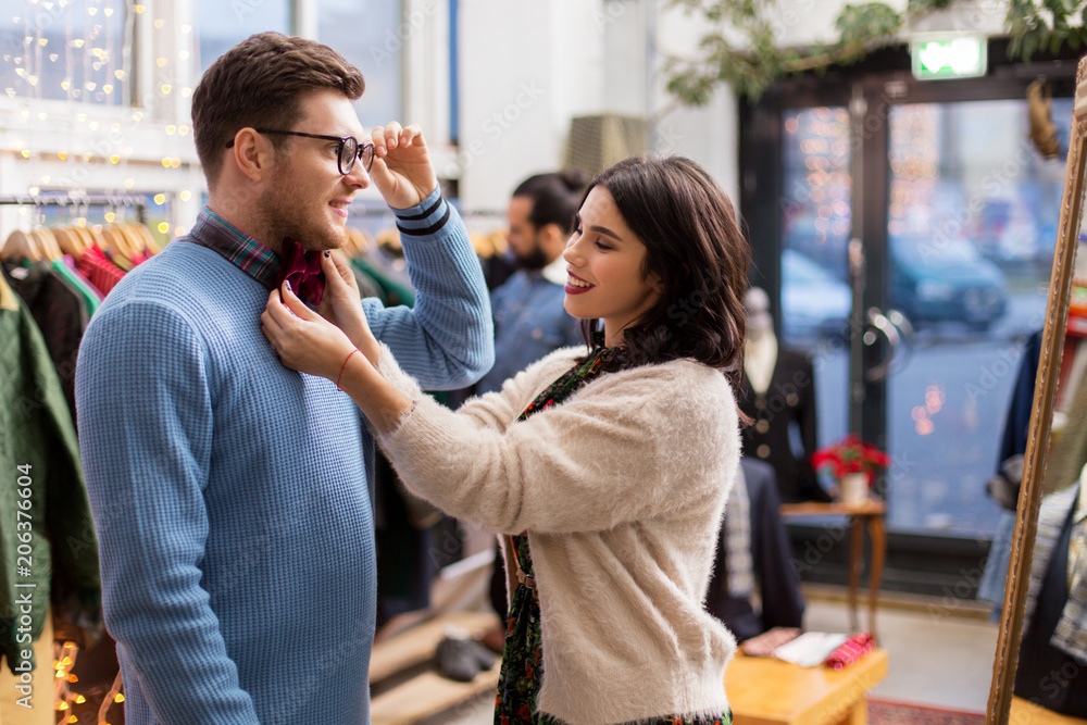 Fototapeta premium sale, shopping, fashion and people concept - couple choosing clothes at vintage clothing store