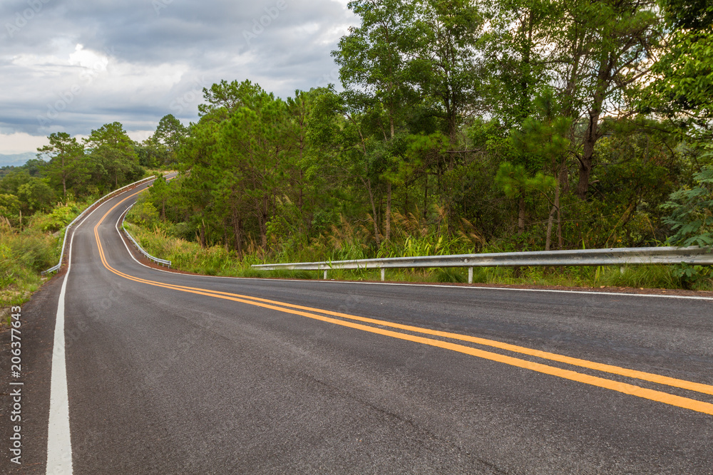 Beautiful mountain asphalt road with curve and double yellow line , road runs along the edge of the forest in chiang mai, Thailand Beautiful mountain asphalt road with curve and double yellow line , road runs along the edge of the forest in chiang mai, Thailand