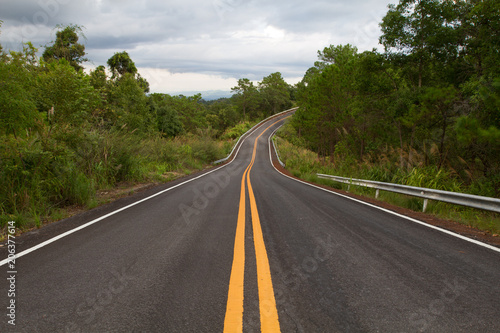 Beautiful mountain asphalt road with curve and double yellow line ,  road runs along the edge of the forest in chiang mai, Thailand