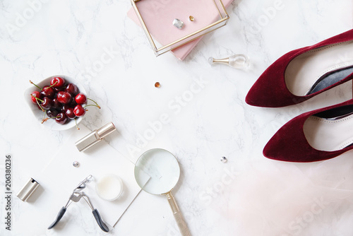 Flatlay with feminine accessories and red high-heeled shoes on marble background