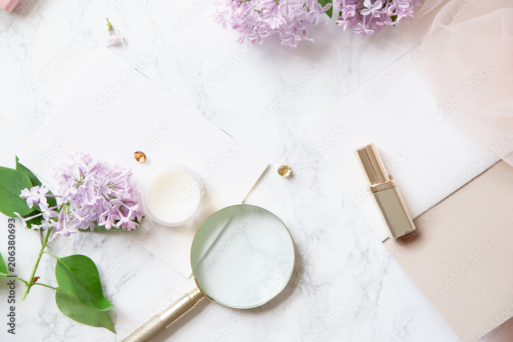 Top vew composition with feminine workspace mock up with lilac flowers and pink accessories on marble background Top vew composition with feminine workspace mock up with lilac flowers and pink accessories on marble background