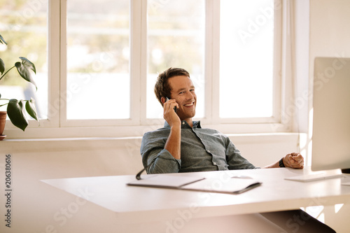 Entrepreneur talking on mobile phone while working on computer a