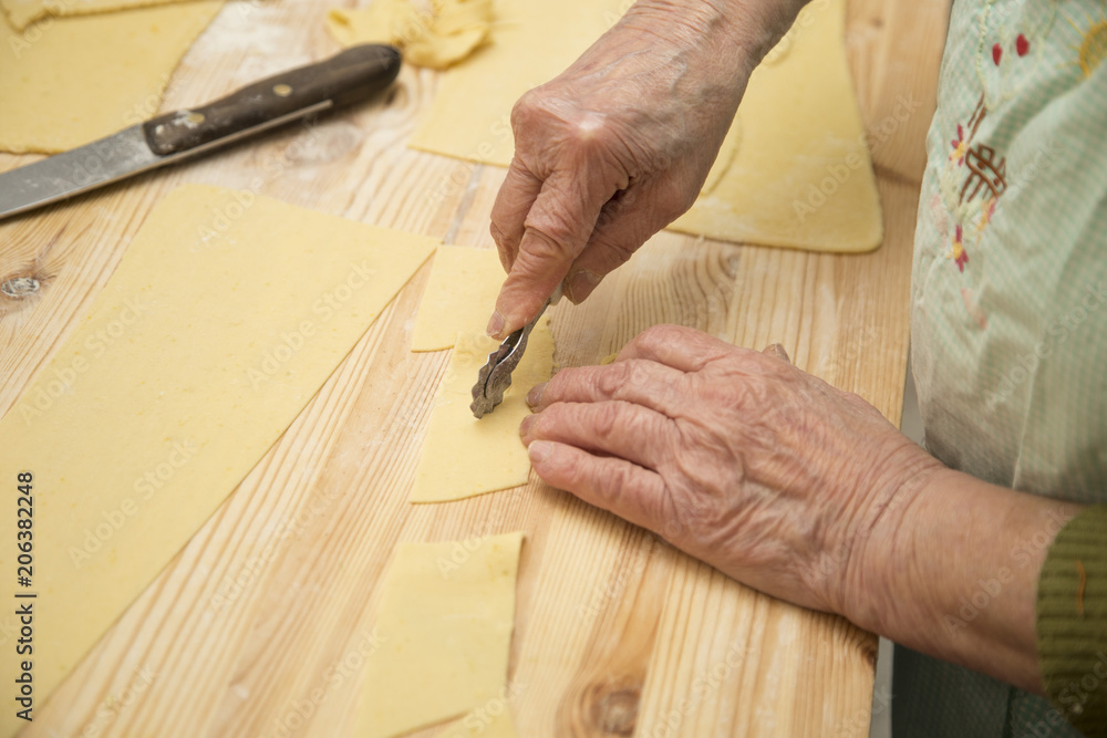 closeup of hands of housewife cutting fresh pasta closeup of hands of housewife cutting fresh pasta