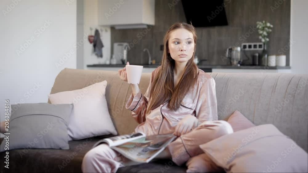 Beautiful young woman sitting in living room Beautiful young woman sitting in living room