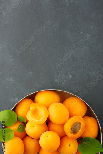 Ripe apricots and apricot leaves on the wooden background.