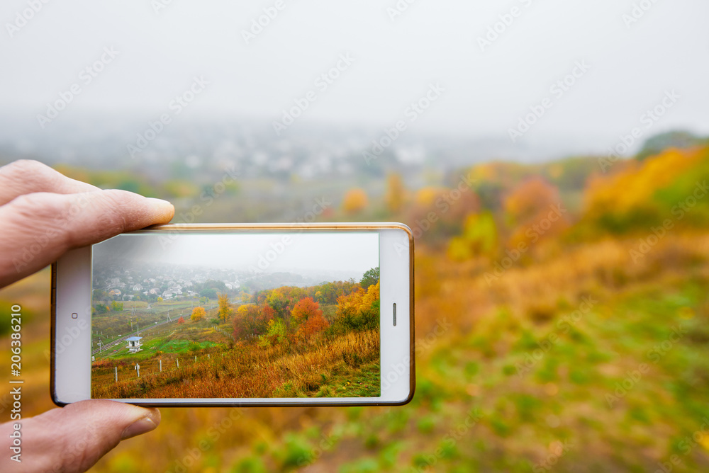 Photo of beautiful autumn background on screen of modern smartphone