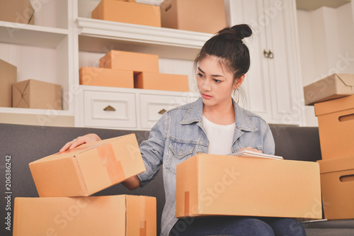 Sme business concept. Young Asian people are packing their packages.Delivery business Small and Medium Enterprise (SMEs). Young man is working in the house.Young Owner Start up for Business Online.