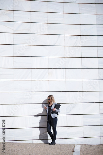 Pretty young business woman using her mobile phone in the street.