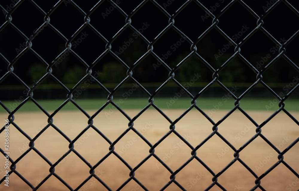 Close up photo of a baseball field fence looking through it to an empty field at night. Great for background use. Close up photo of a baseball field fence looking through it to an empty field at night. Great for background use.