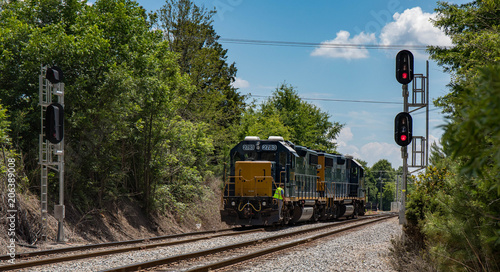 Quadro su tela A long view of two railroad cars with flashing signals and an engineer standing on the back