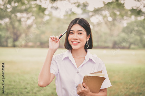 Education Concepts. Beautiful student reading books in the park. Beautiful girl are relaxing in the park. Young student are happy to read. Young student love to study. Education of Asian Women.