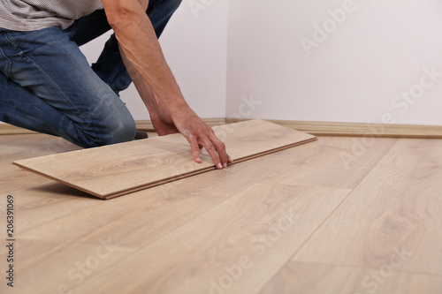 Man installing new laminated wooden floor close up