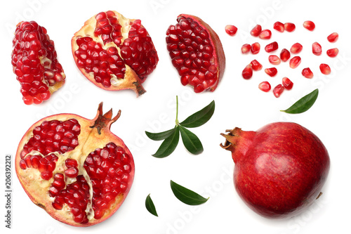 pomegranate fruit with seeds and green leaves isolated on white background top view