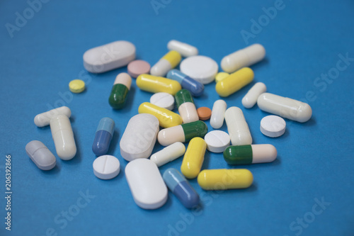 Pills are scattered over a blue background. Close up. Medical background.