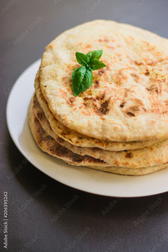 tortillas with potatoes, pita, chapati, decorated with a leaf of basil, on a black background, oriental food