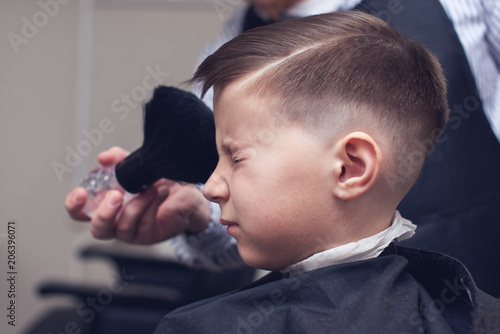 Barber making a haircut to a boy using brush.