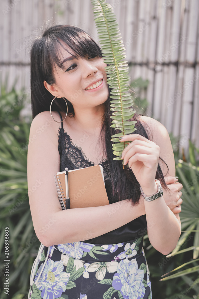 Naklejka premium Education Concepts. Asian women reading books in the park. Beautiful women are relaxing in the park. Beautiful women are happy to read.