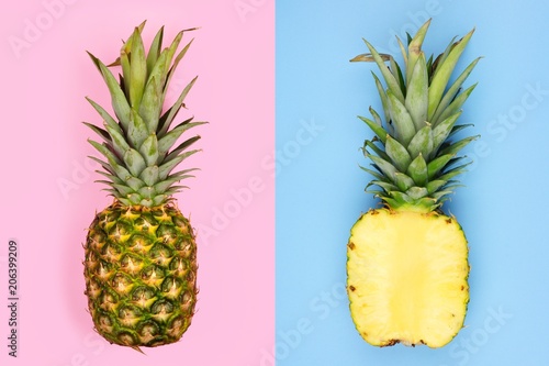 Creative pineapple layout. Whole fruit on pastel pink, half slice with blue background. Minimal summer concept Top view.