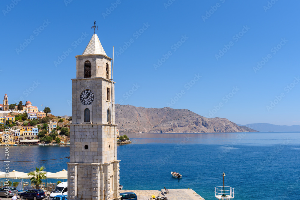 Clock tower Symi and blue sea. Symi island, Greece