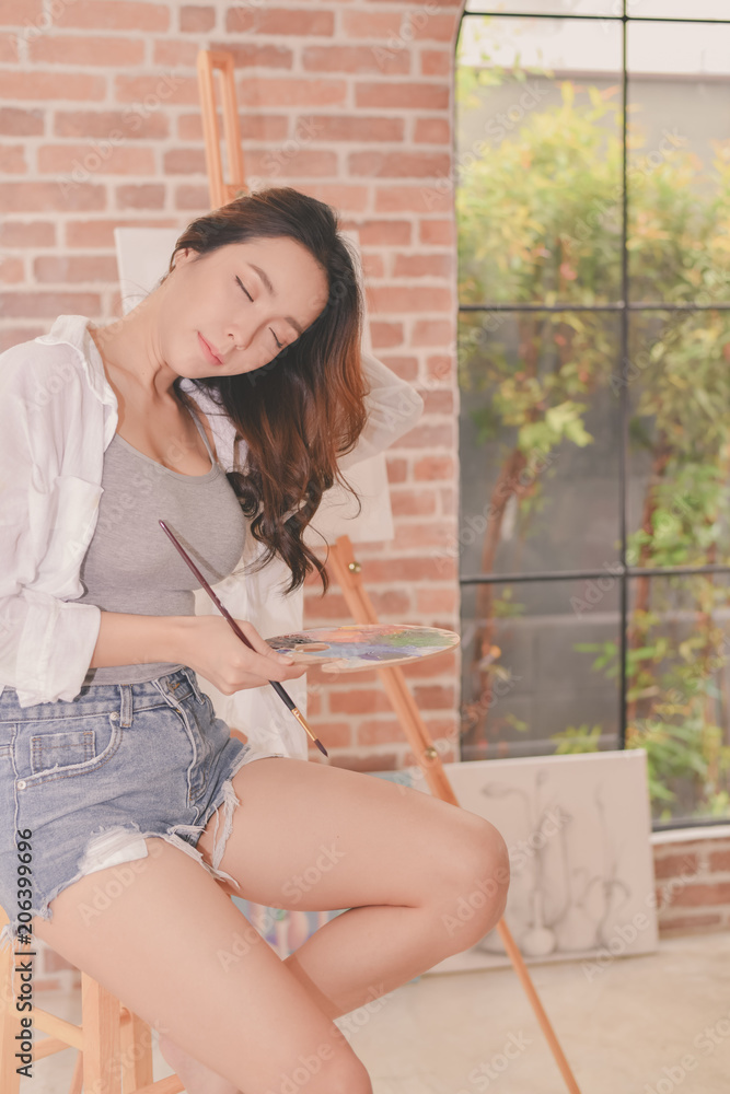 Fototapeta premium Concept Artist Beautiful girl. Beautiful women are creating art. Beautiful woman is painting happily. Young artist painting in the gallery.