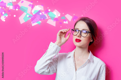 Beautiful redhead businesswoman in white shirt with abstract colored ideas on pink background