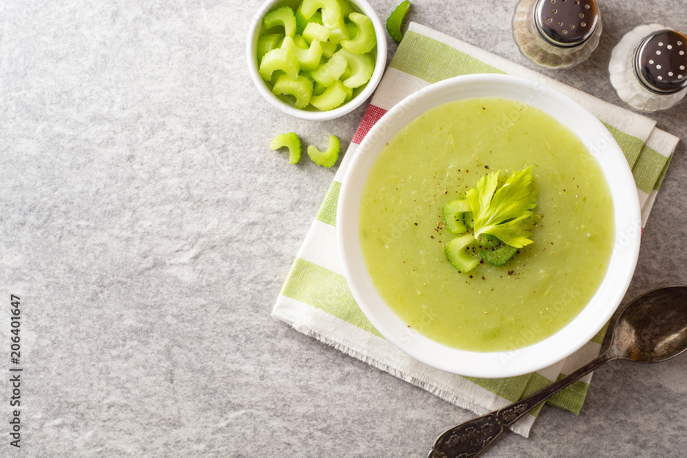 Celery cream soup in white plate on gray stone background Celery cream soup in white plate on gray stone background