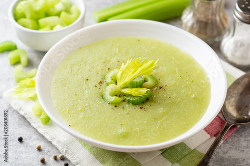 Celery cream soup in white plate on gray stone background