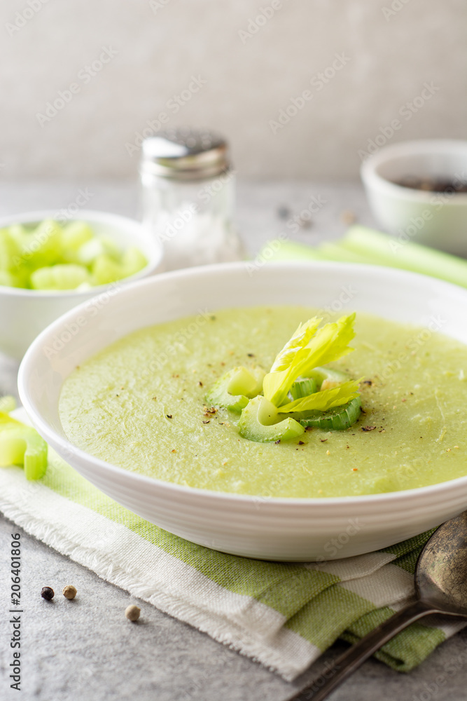 Celery cream soup in white plate on gray stone background Celery cream soup in white plate on gray stone background