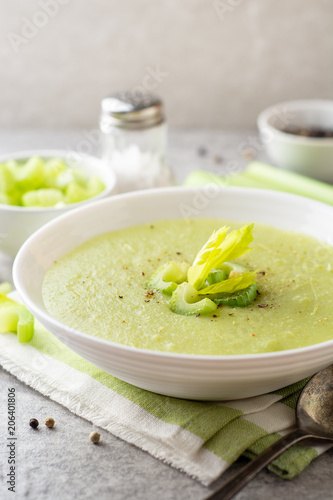 Celery cream soup in white plate on gray stone background