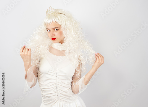 Confident and flirtatious young woman with tiara on light background
