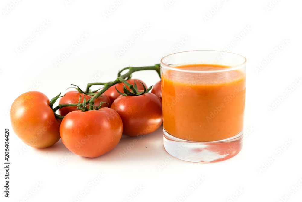 tomato on branch and glass of tomato soup or gazpacho on white background tomato on branch and glass of tomato soup or gazpacho on white background