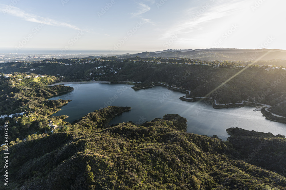 Aerial view of Stone Canyon Reservoir and late afternoon sunshine with Los Angeles and pacific coast in background.