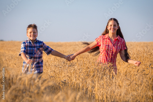 girl and boy running on field with ripe wheat