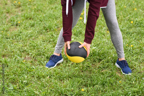 cropped view of woman training with medicine ball on green grass