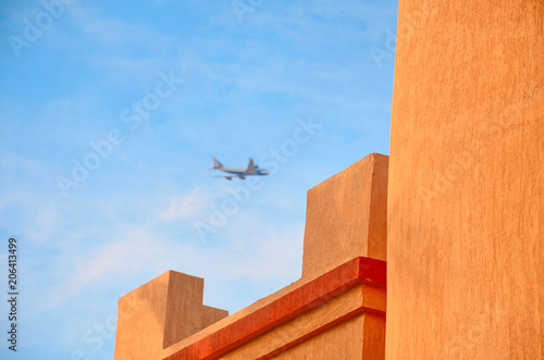 travel concept part of the hotel building and flying plane in blue sky in the defocus